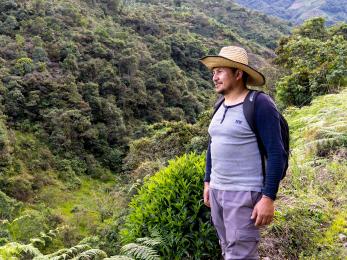 Colombia man stands amidst rural setting, looking over a valley.