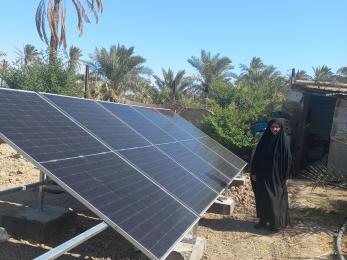 Iraqi woman standing beside solar array.