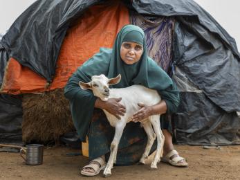 Kenyan woman with goat in front of tent.