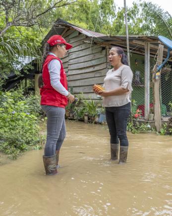 Mercy Corps Colombia employee speaks with community member standing in flood waters.