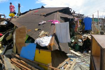 Alan Habinada stands on the roof of a collapsed house during his first visit to his hometown since the typhoon struck. He returned to bring relief goods to his mother and look for his missing fiancée. Sadly, he learned a few hours later that she had been killed.
