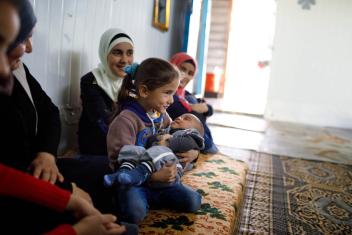 Baby supplies are tremendously helpful for growing refugee families like Eman’s (blue headscarf). She lives in a caravan in Zaatari with her newborn, Inas, and her other children. Photo: Annie Sakkab/Mercy Corps