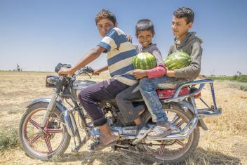 Abu Goubran's son Safouan (center, 12) and his friends bring recently harvested watermelon home on a motorcycle.