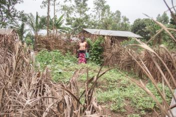 Grace Ganisikale works in her permargarden which is protected by a fence made of palm fronds. She built her garden with help from Mercy Corps.