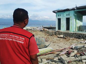 Arianto, senior program officer, surveys a plea for help spray painted in malay ("tolong"), on the ruins of a building in the devastated coastal village, loli tondo. photo: genadi aryawan for mercy corps