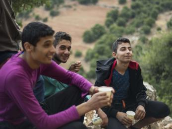 Three young men holding cups and sitting