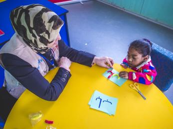 Haleema, a shadow teacher, working with malak at a table