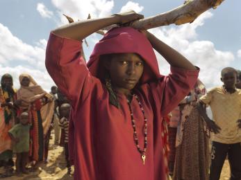 Girl holding a large stick over her head with people in the background