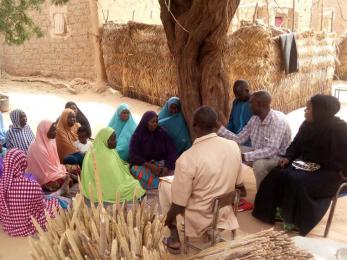 A group of community members gathered outdoors, seated