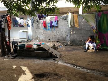 Girl sitting outside with clothes hanging nearby