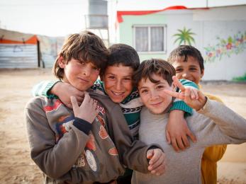 Four boys smiling together, one holding up a peace sign