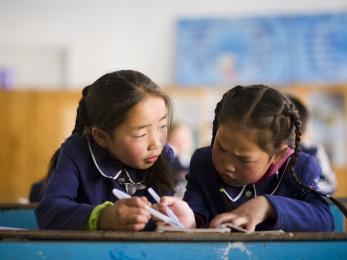 Two girls writing at a desk in mongolia