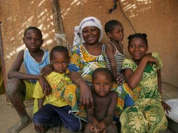 Woman with five children sitting outside house