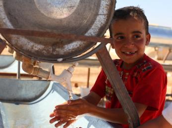 Boy washing hands at refugee camp water station