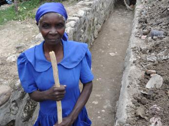 Haitian woman pictured cleaning and renovating a drainage ditch.