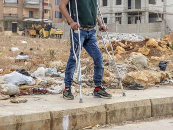 Disabled individual standing in front of empty lot.