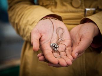 Hands holding a necklace with a heart pendant