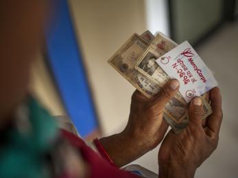 Image: hands holding cash and a mercy corps id card during a distribution of emergency cash