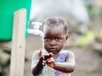 A child washes hands at a hygiene station in a displacement camp on the outskirts of goma, drc. in 2015, when this photo was taken, about 5,000 people lived in the camp because of ongoing violence and political instability in eastern congo. photo: corinna robbins/mercy corps