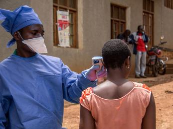 Habibu, hygienist at the malepe health center in drc, takes the temperature of every person who enters the health center after attending our training about preventing the spread of the ebola virus epidemic. photo: rudy nkombo/mercy corps