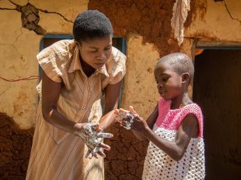 Woman showing child how to wash hands