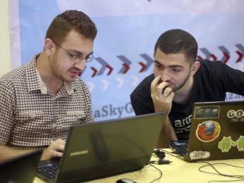 Two men working together on laptops