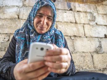 A syrian refugee uses her mobile phone to access digital banking services in jordan.