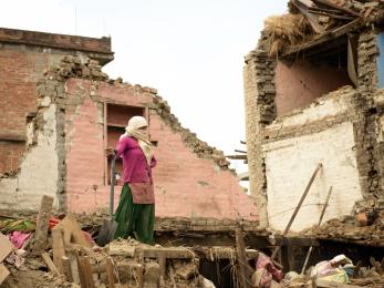 A woman in nepal standing among rubble after the earthquake