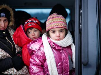 A young girl in a pink coat, hat and scarf