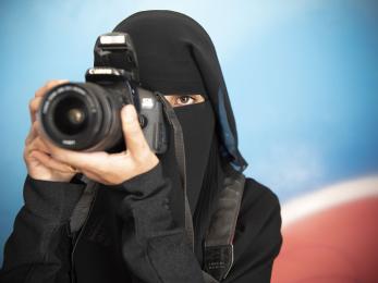 A woman holds a camera to her eye in yemen