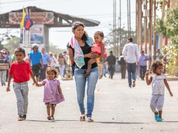 Mother, baby, and young children walking down a road