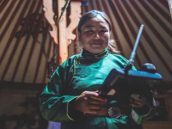 A mongolian animal herder uses an sms forecasting system device to monitor local weather.