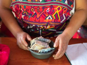 The hands of a savings and loan group grasp a bowl of paper money in acul, guatemala.