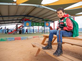 A young boy sitting at a playground in jordan