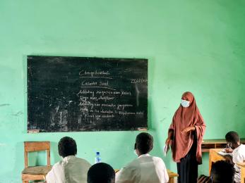 An instructor leads a class while standing at a chalk board.