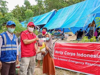 Humanitarian aid team members hand food to a participant.