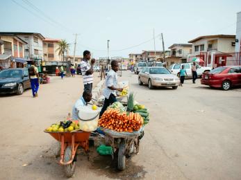 People selling fruits and vegetables on a busy street.