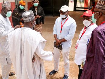 A small group of people stand together talking.