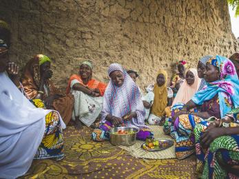 A group of people sitting together while someone prepares food.