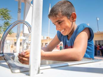 A young person washing their hands.