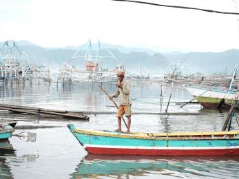 A man riding his boat in coastal neighborhood in pulau pasaran bandar lampung, indonesia.