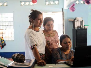 Three people using a computer.