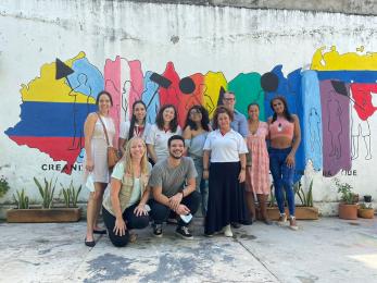 Mercy corps colombia team members and participants stand in front of a mural celebrating unity.