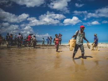 Mercy corps staff and locals crossing flooded areas on foot.