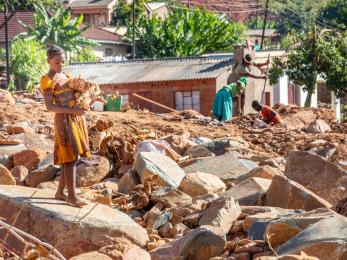 A young person carries debris from one of the many landslides that crisscross ngangu in the aftermath of cyclone idai.