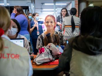 A person holding their child while speaking with mercy corps staff at a health clinic in medellín, colombia.