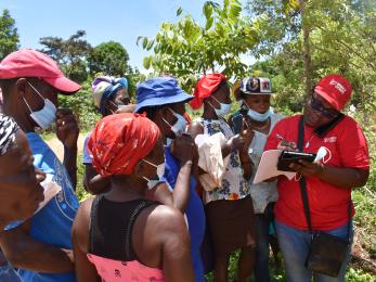 In grand'anse, haiti, a mercy corps team member helps farmers set up mobile accounts for emergency cash aid transfers. 