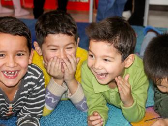 Four young children lying on a floor and laughing