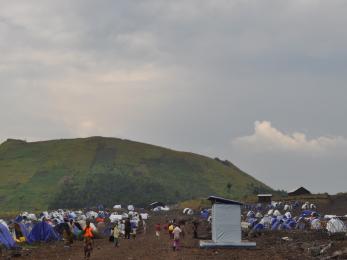 Families move about a camp with temporary living structures.