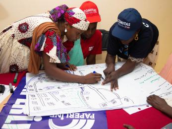 Three people draw maps together on a table.